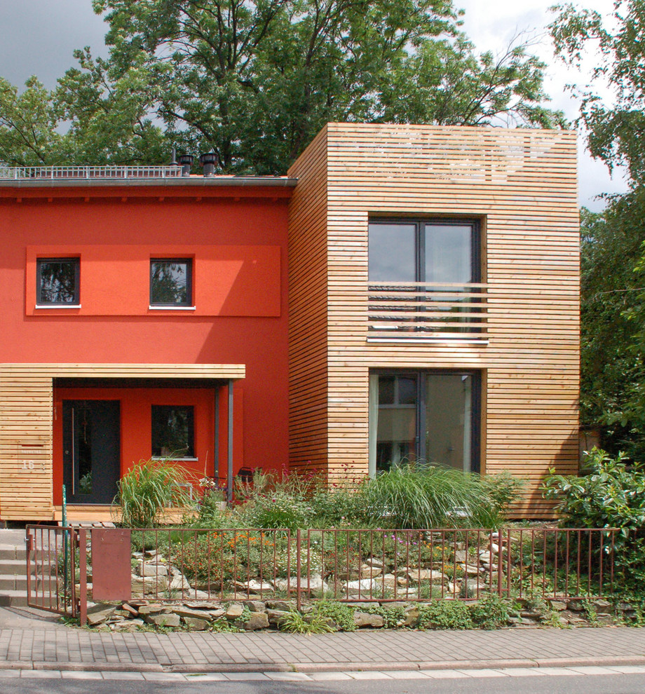 Foto de fachada roja contemporánea de dos plantas con revestimiento de madera y tejado a dos aguas