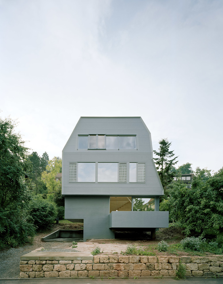 Foto på ett mellanstort funkis grått hus, med tre eller fler plan och platt tak