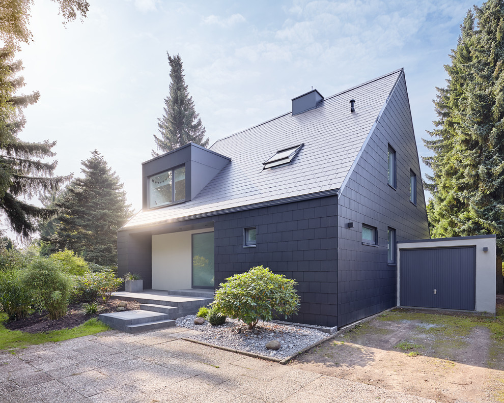 Exemple d'une façade de maison noire tendance en panneau de béton fibré avec un toit à deux pans.
