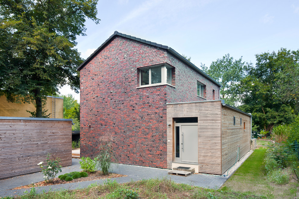 Пример оригинального дизайна: двухэтажный, красный дом среднего размера в классическом стиле с двускатной крышей и комбинированной облицовкой