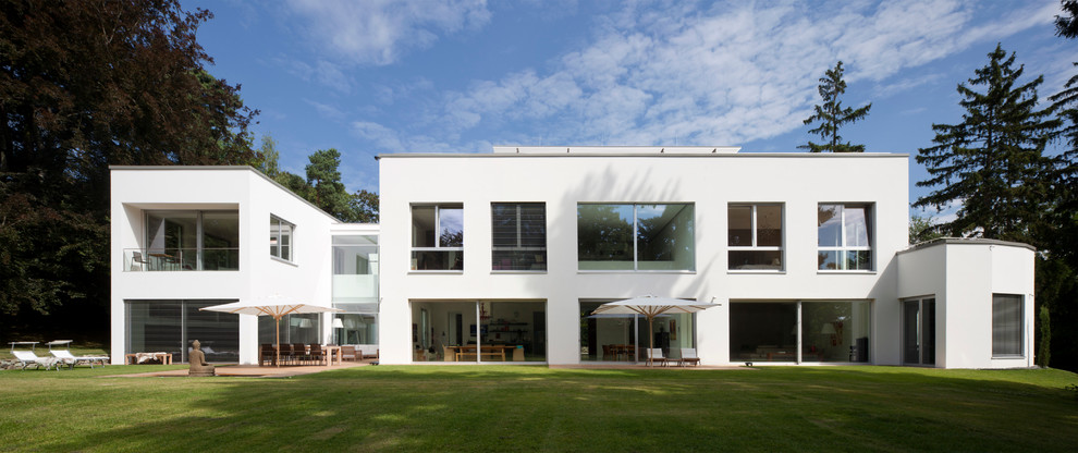Cette image montre une grande façade de petite villa blanche minimaliste à un étage avec un toit plat.