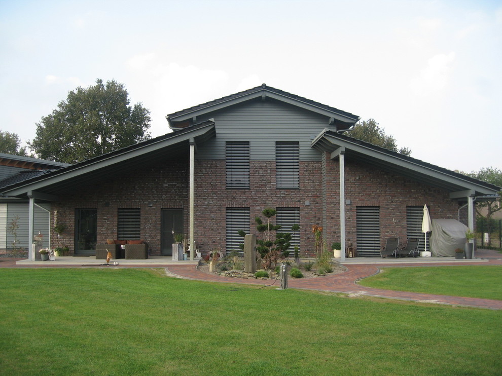 This is an example of a large and brown contemporary two floor brick house exterior in Bremen with a hip roof.