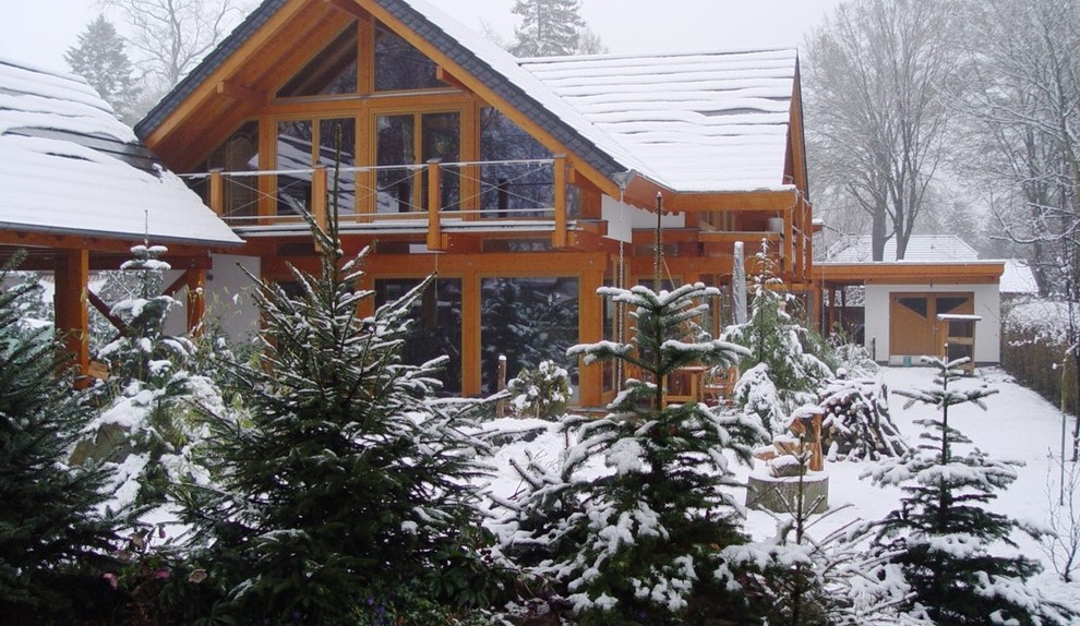 Cette photo montre une très grande façade de maison beige nature en bois à un étage avec un toit à deux pans et un toit en tuile.