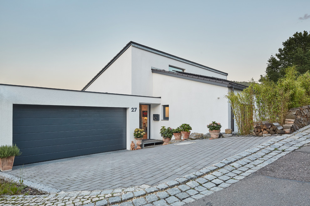 Photo of a white contemporary bungalow detached house in Nuremberg with a lean-to roof and a tiled roof.