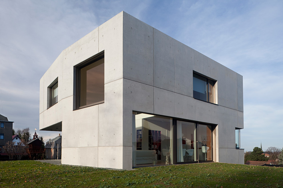 Esempio della facciata di una casa grigia contemporanea a due piani di medie dimensioni con rivestimento in cemento e tetto piano