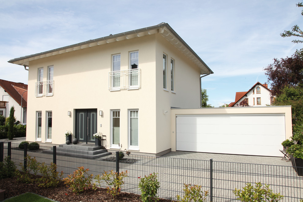 Yellow contemporary two floor render detached house in Other with a hip roof and a tiled roof.