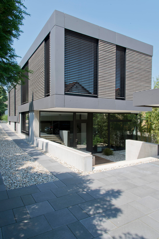 Foto della facciata di una casa grande grigia contemporanea a due piani con rivestimento in cemento e tetto piano