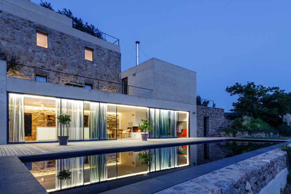 На фото: двухэтажный, большой, серый дом в средиземноморском стиле с комбинированной облицовкой и плоской крышей