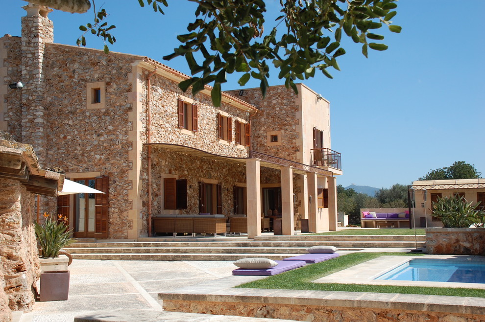 На фото: большой, двухэтажный, бежевый дом в средиземноморском стиле с облицовкой из камня и двускатной крышей с