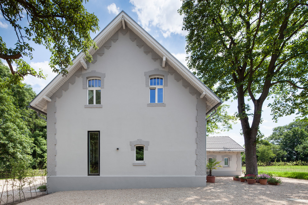 На фото: большой, серый, двухэтажный дом в скандинавском стиле с комбинированной облицовкой и двускатной крышей с