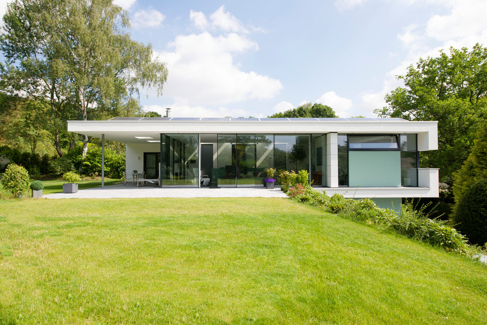 Modelo de fachada de casa blanca moderna grande de dos plantas con revestimiento de estuco y tejado plano