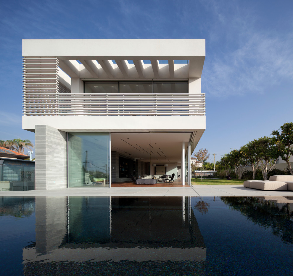 Стильный дизайн: большой, двухэтажный, белый частный загородный дом в стиле модернизм с облицовкой из цементной штукатурки и плоской крышей - последний тренд