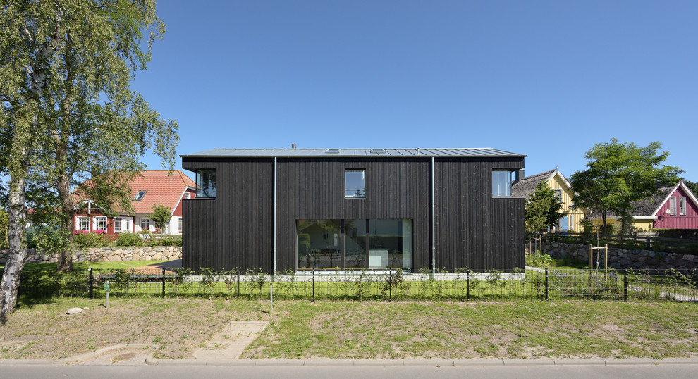 Immagine della facciata di una casa grande nera contemporanea a due piani con rivestimento in legno e tetto a capanna