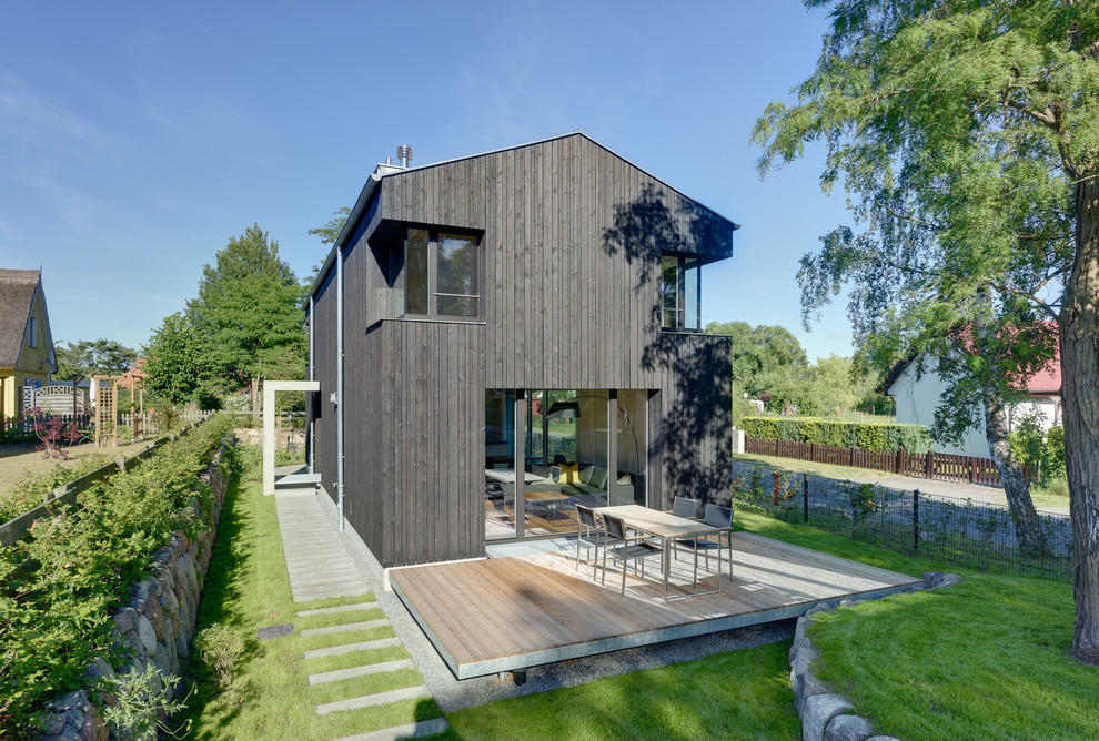 На фото: большой, деревянный, черный, двухэтажный дом в современном стиле с двускатной крышей с