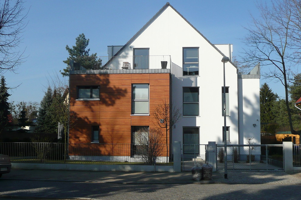 Inspiration for a medium sized modern house exterior in Berlin with three floors, mixed cladding and a pitched roof.