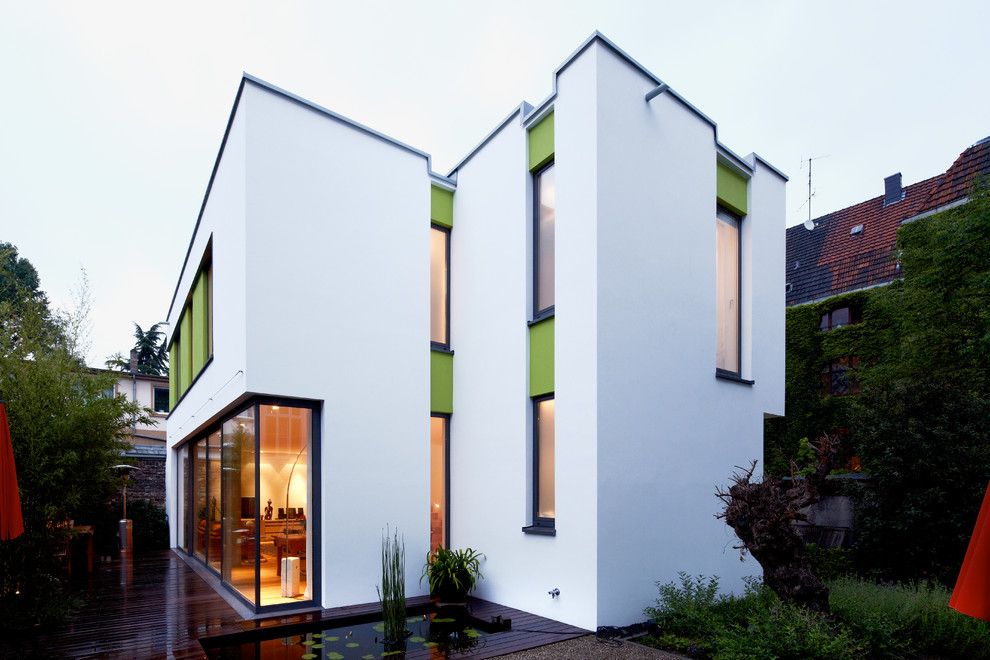Cette image montre une grande façade de maison blanche design en stuc à un étage avec un toit plat.