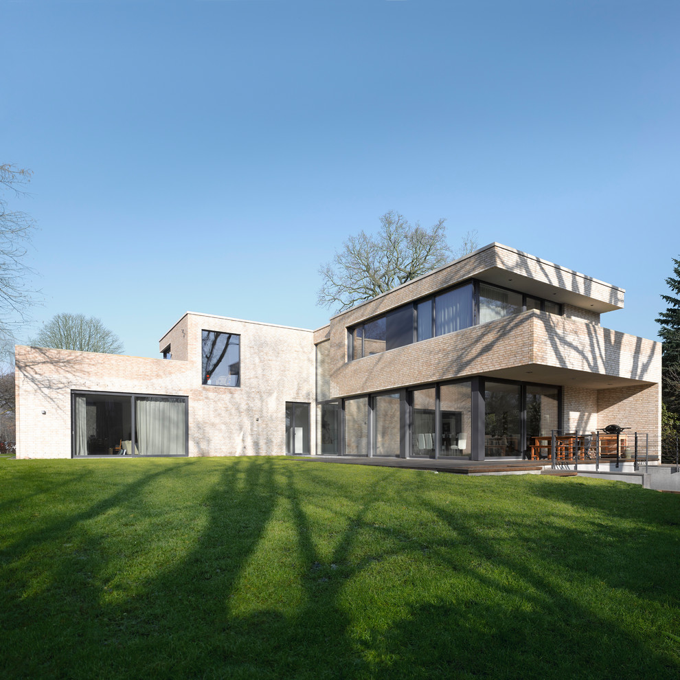 Foto della villa ampia beige contemporanea a due piani con rivestimento in mattoni e tetto piano