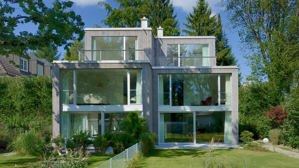 Стильный дизайн: большой, трехэтажный, деревянный, серый дом в современном стиле с плоской крышей - последний тренд