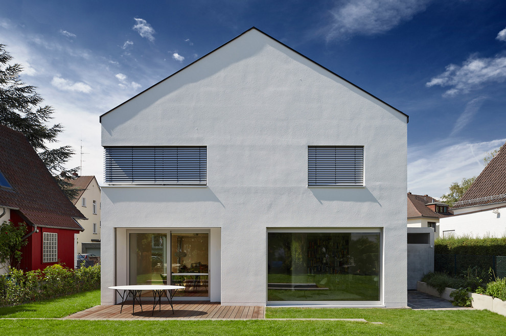 На фото: двухэтажный, белый, большой дом в современном стиле с двускатной крышей с