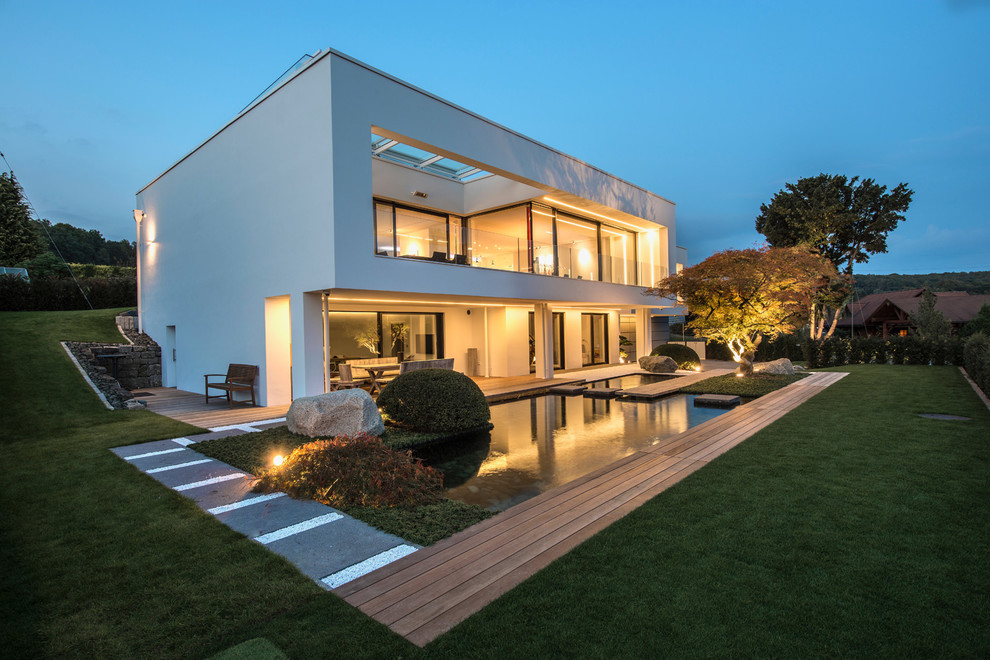 Diseño de fachada de casa blanca contemporánea grande de dos plantas con revestimiento de estuco y tejado plano