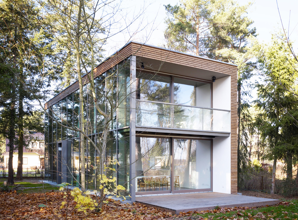Foto della facciata di una casa contemporanea a due piani di medie dimensioni con rivestimento in vetro e tetto piano