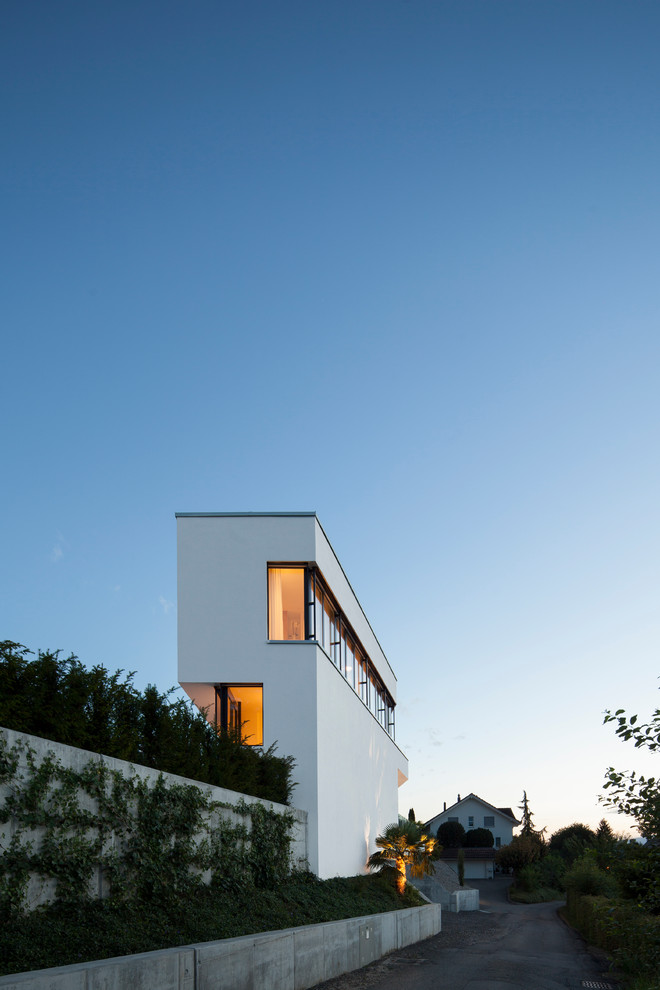 Источник вдохновения для домашнего уюта: большой, трехэтажный, серый частный загородный дом в современном стиле с облицовкой из цементной штукатурки и плоской крышей