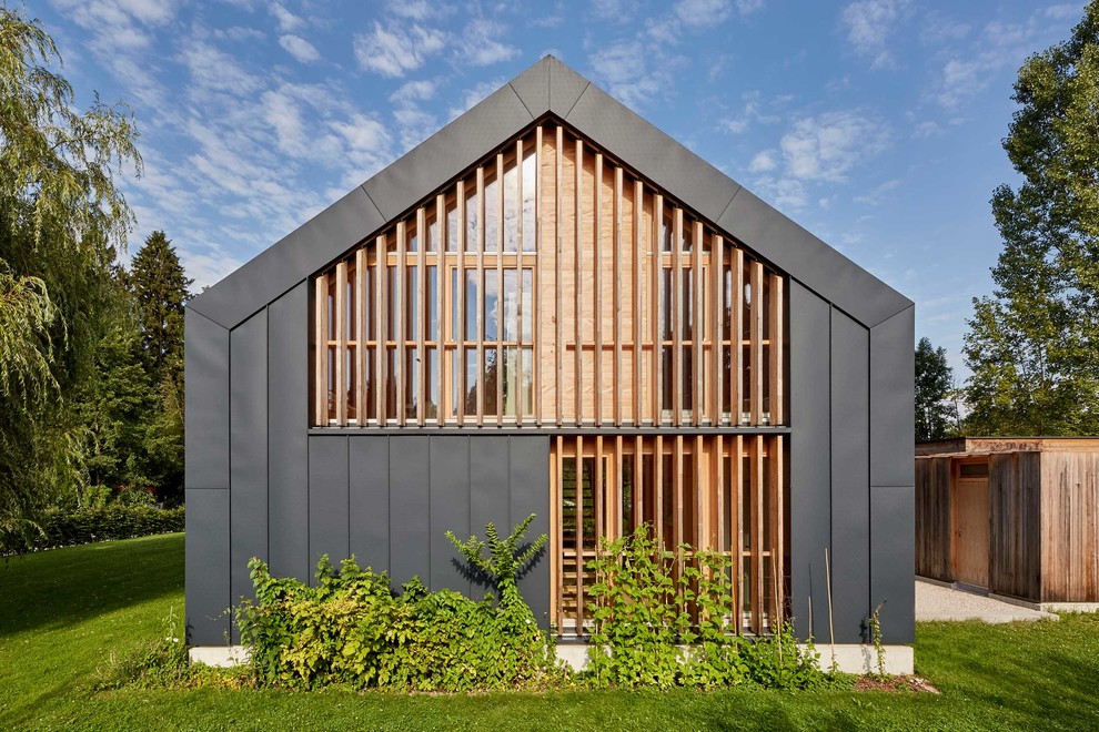 Zweistöckiges Modernes Einfamilienhaus mit Mix-Fassade, grauer Fassadenfarbe und Satteldach in München