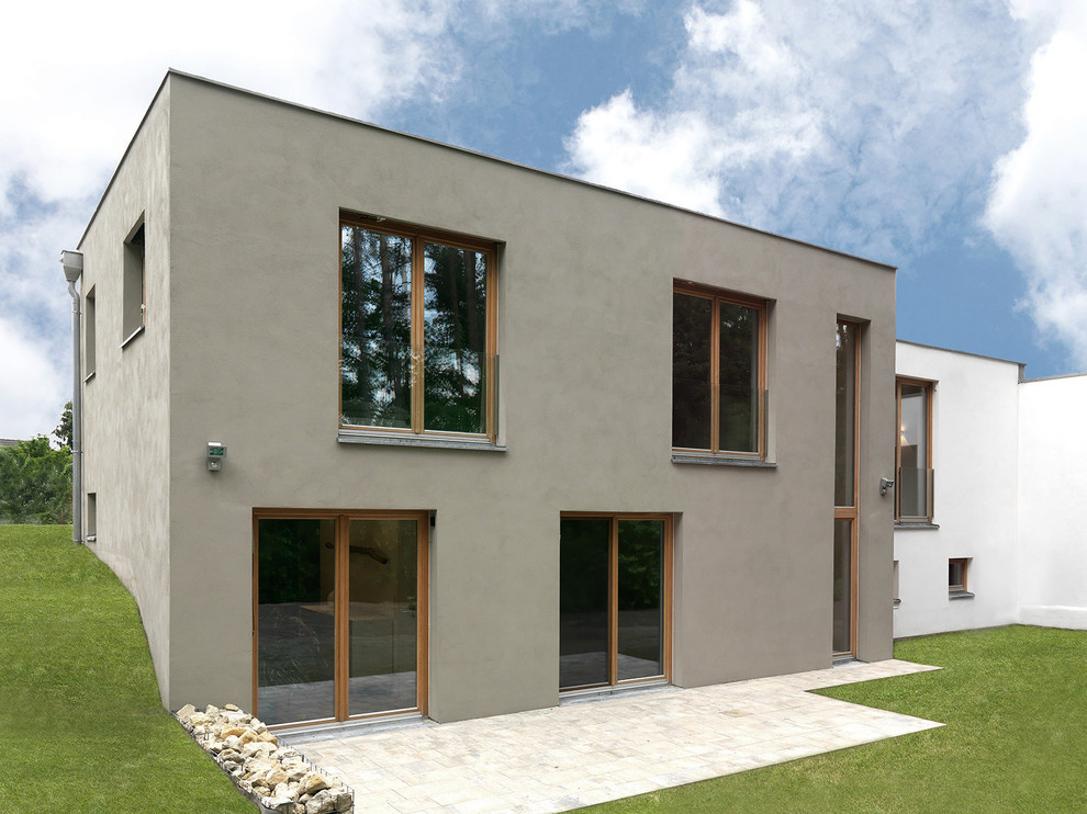 Cette image montre une façade de maison grise design à un étage et de taille moyenne avec un toit plat.