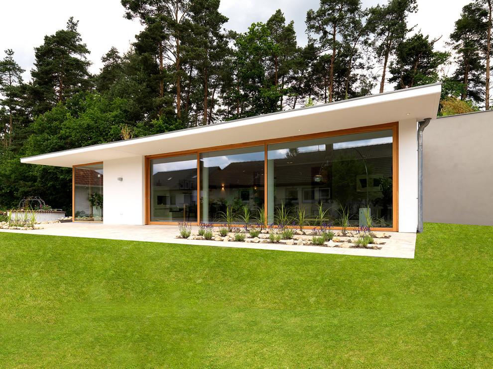 Design ideas for a white and medium sized contemporary bungalow house exterior in Nuremberg with a flat roof.