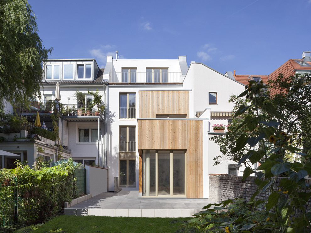 Photo of a white and medium sized contemporary house exterior in Cologne with three floors, mixed cladding and a flat roof.