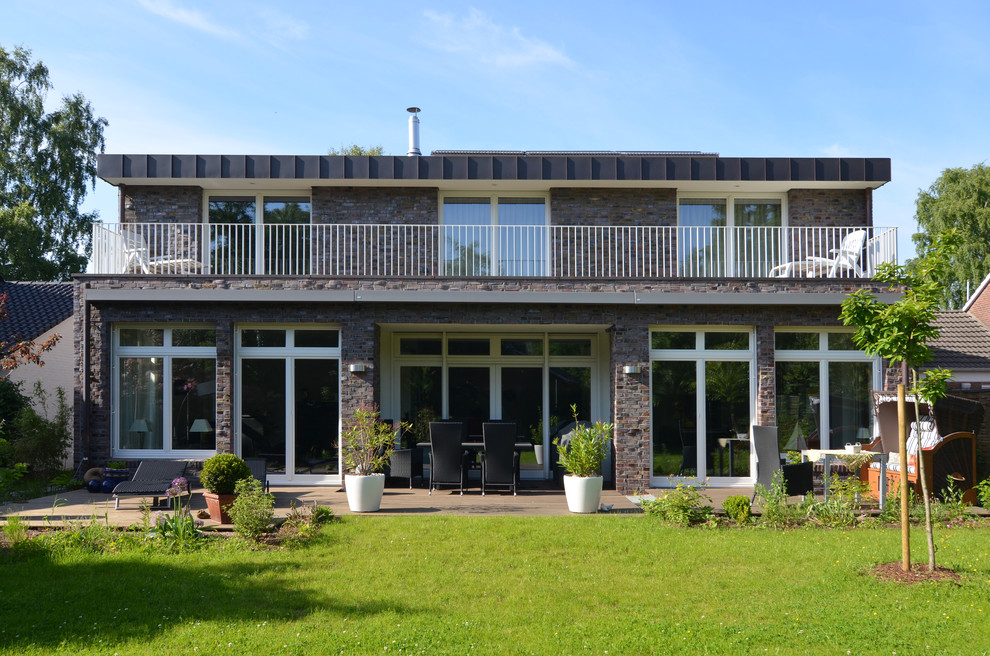 Imagen de fachada actual de tamaño medio de dos plantas con revestimiento de ladrillo y tejado plano