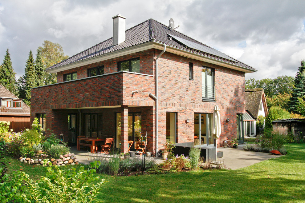 Medium sized and red contemporary two floor brick house exterior in Hamburg with a hip roof.