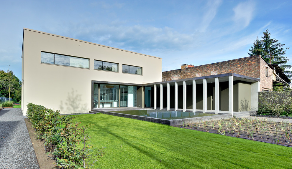 Cette image montre une façade de maison grise design en stuc de taille moyenne et à un étage avec un toit plat.