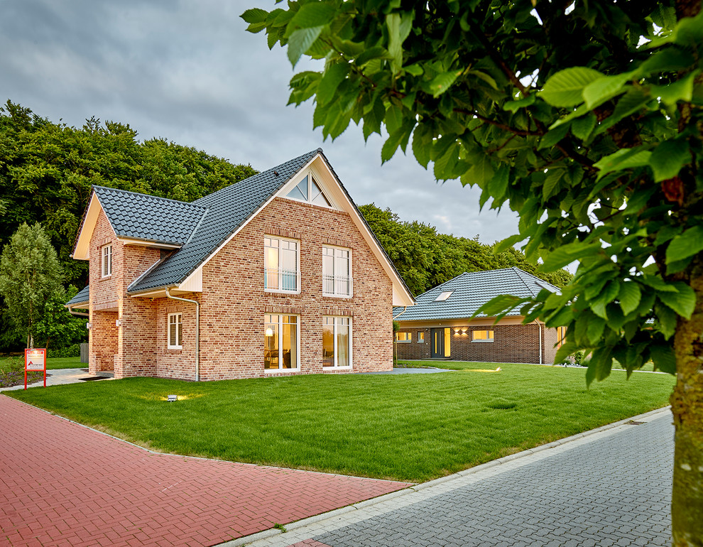 Exemple d'une grande façade de maison rouge tendance en pierre de plain-pied avec un toit à deux pans et un toit en tuile.