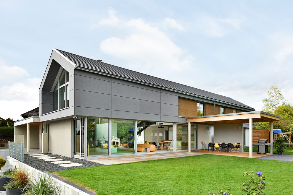 Trendy gray two-story glass exterior home photo with a tile roof