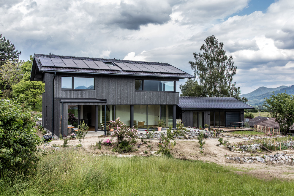 Modelo de fachada de casa gris y gris actual de dos plantas con revestimiento de madera, tejado a dos aguas y tejado de teja de barro