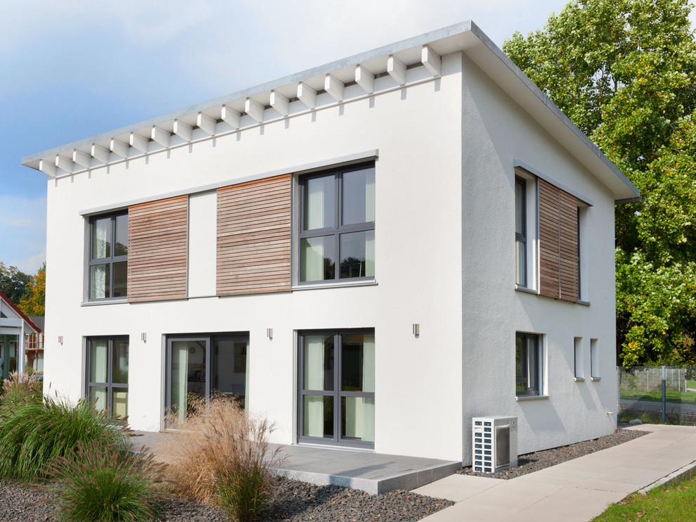 Esempio della facciata di una casa beige contemporanea a due piani di medie dimensioni con rivestimento in stucco e copertura verde
