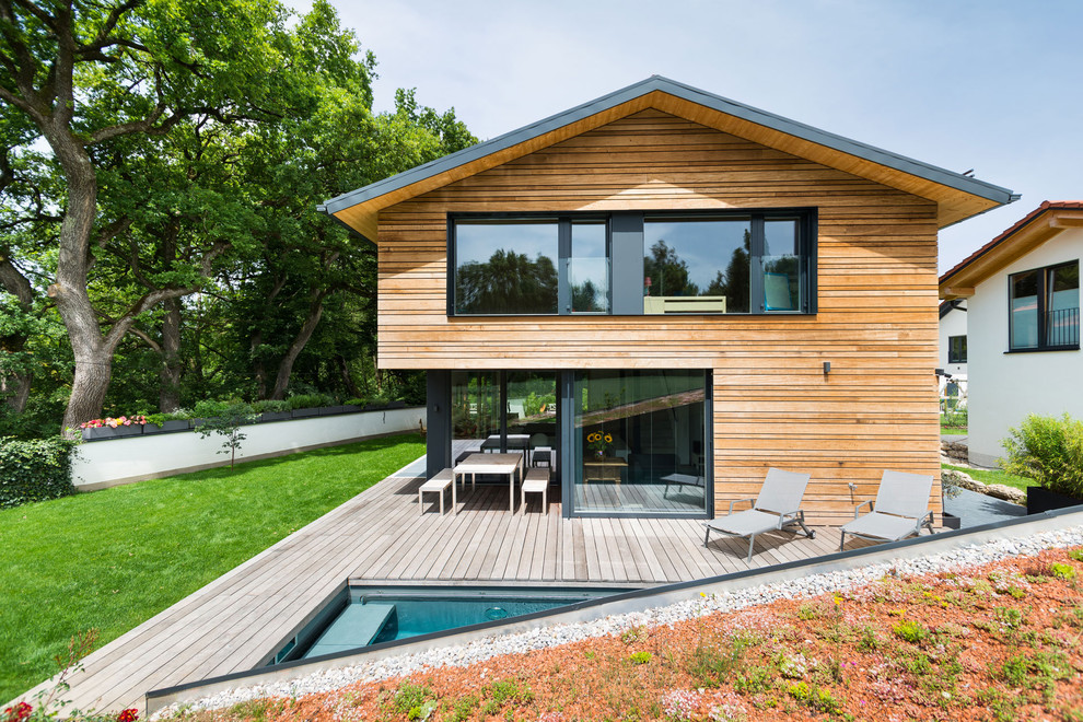 На фото: двухэтажный, деревянный, коричневый дом среднего размера в современном стиле с двускатной крышей с