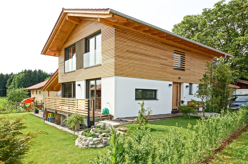 Foto de fachada de casa marrón de estilo de casa de campo de tamaño medio a niveles con revestimiento de madera, tejado a dos aguas y tejado de teja de barro