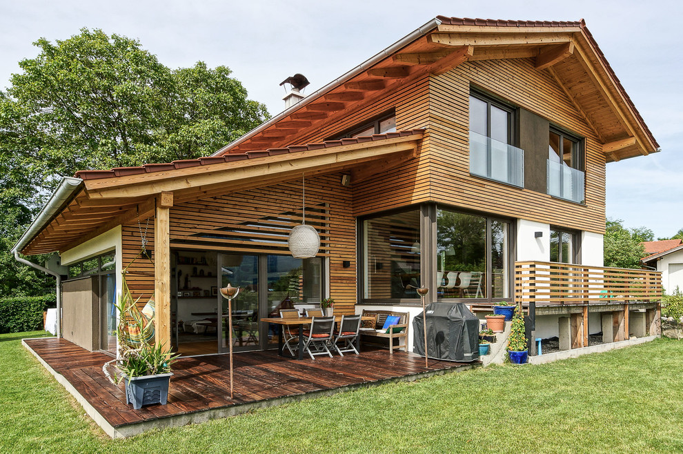 Foto de fachada de casa marrón campestre de tamaño medio de dos plantas con revestimiento de madera, tejado a dos aguas y tejado de teja de barro