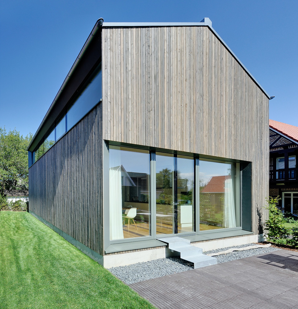 Mittelgroße, Zweistöckige Moderne Holzfassade Haus mit brauner Fassadenfarbe und Satteldach in Berlin