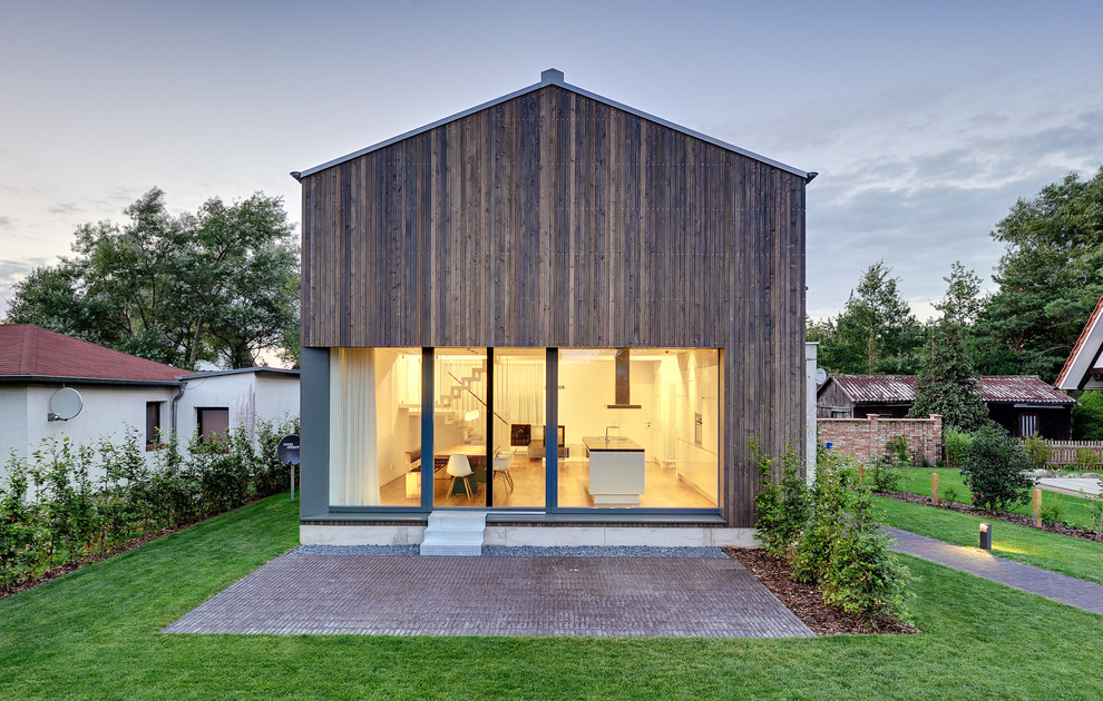 Mittelgroße, Zweistöckige Moderne Holzfassade Haus mit Satteldach und brauner Fassadenfarbe in Berlin