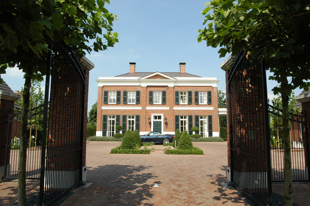 Esempio della facciata di una casa rossa classica a due piani di medie dimensioni con rivestimento in mattoni e tetto a padiglione