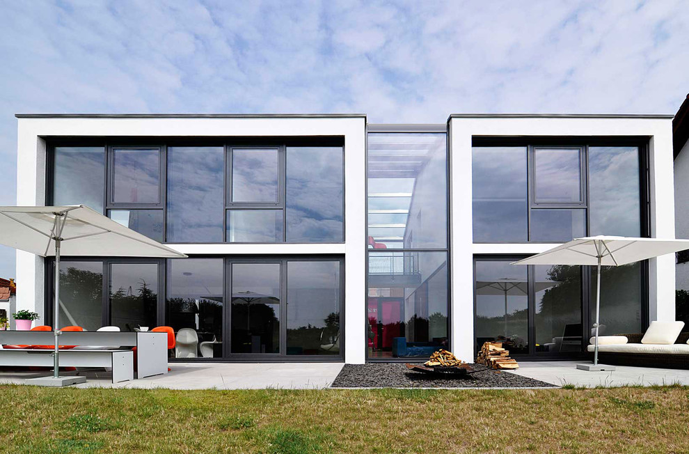 На фото: двухэтажный, белый дом среднего размера в стиле модернизм с облицовкой из цементной штукатурки и плоской крышей