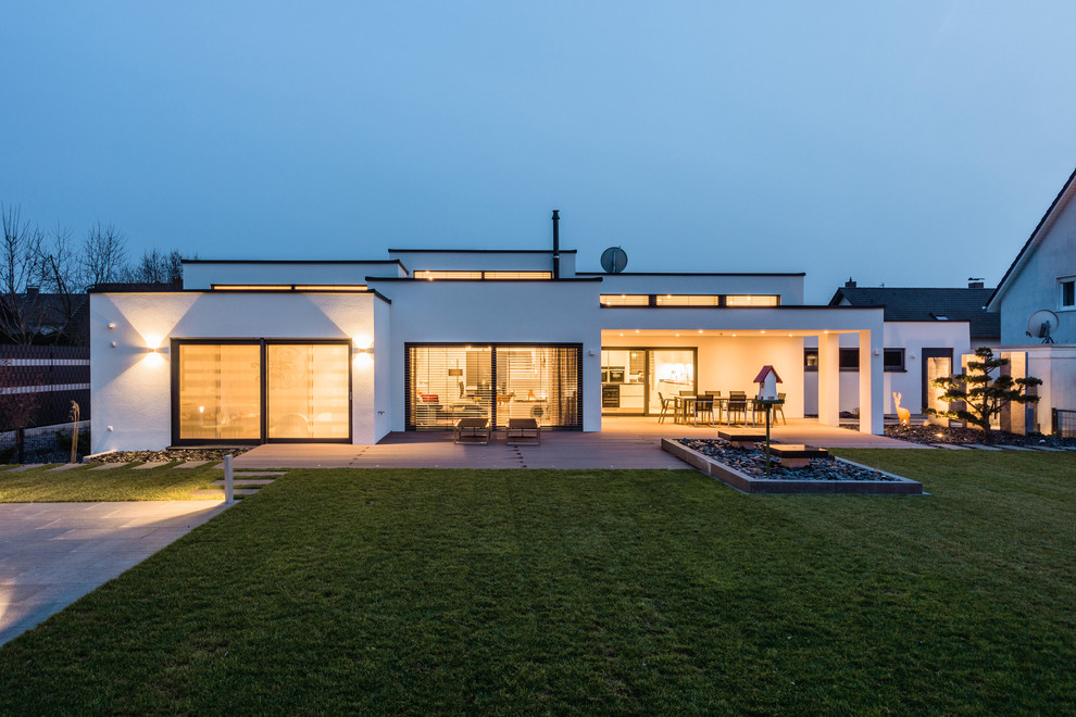 Стильный дизайн: большой, белый, двухэтажный дом в современном стиле с облицовкой из цементной штукатурки и плоской крышей - последний тренд