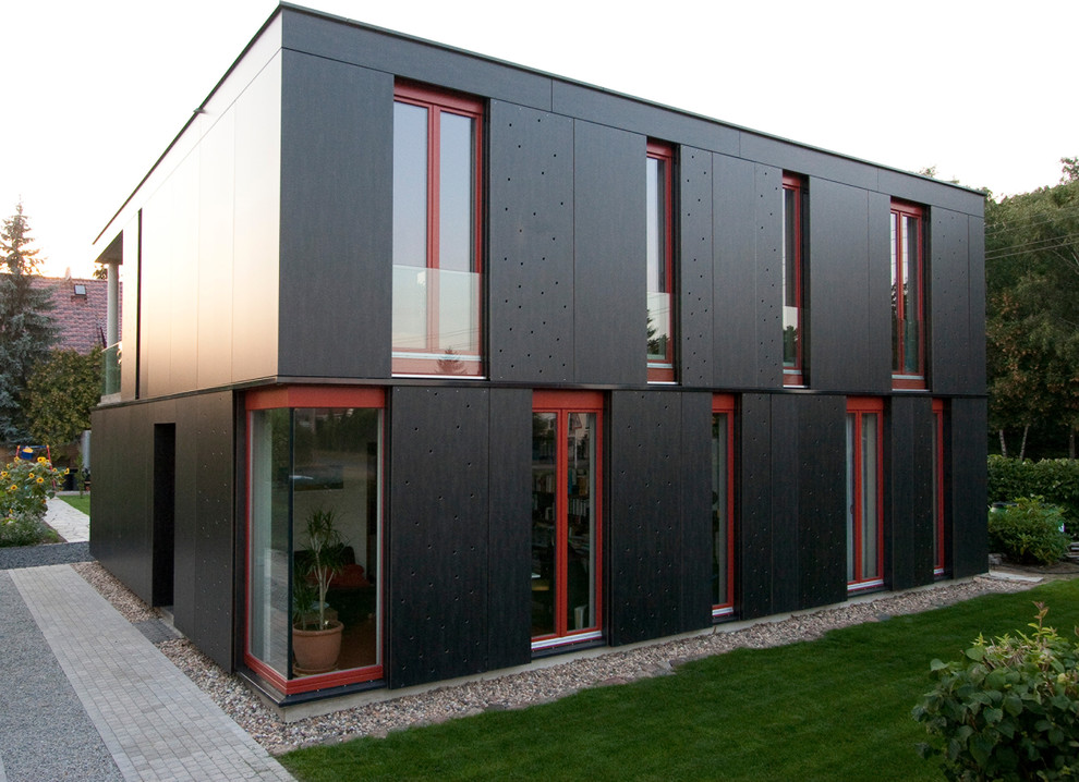 Modelo de fachada negra actual grande de dos plantas con tejado plano y revestimiento de madera