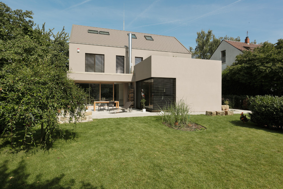 Cette image montre une façade de maison beige design de taille moyenne et à deux étages et plus avec un toit à deux pans.