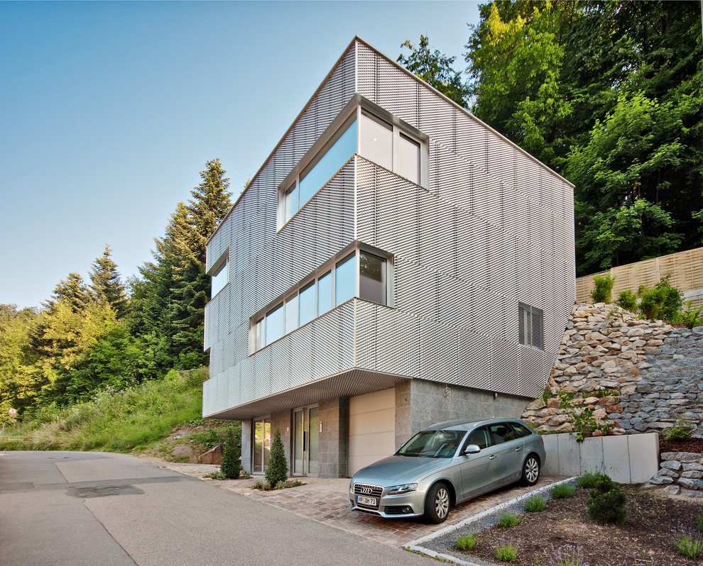 Пример оригинального дизайна: большой, трехэтажный дом в современном стиле с облицовкой из металла и плоской крышей