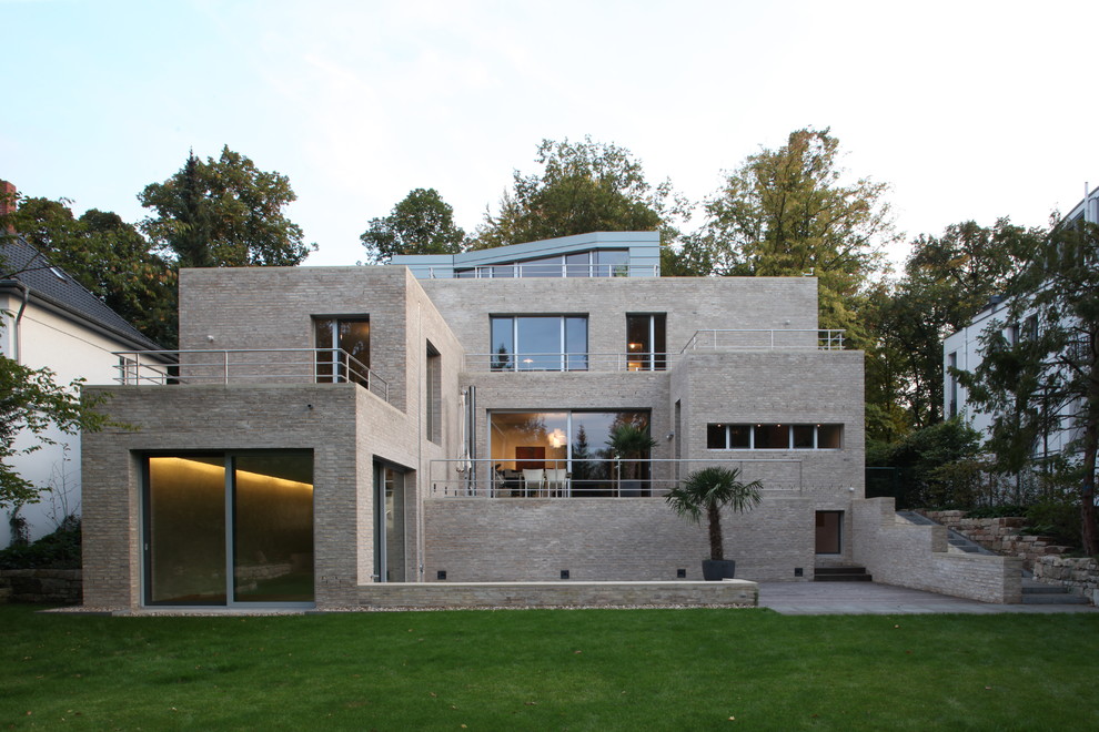 Inspiration for an expansive and gey contemporary brick house exterior in Berlin with three floors and a flat roof.