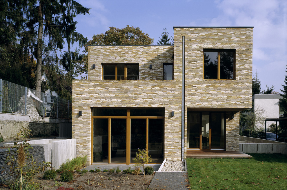 Idee per la facciata di una casa beige moderna a due piani di medie dimensioni con rivestimento in mattoni e tetto piano
